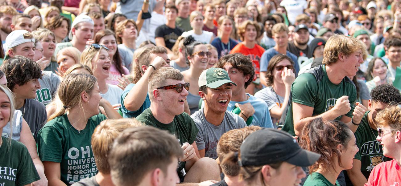 A group of Ohio University students laugh and smile together after sitting in the stands of a stadium