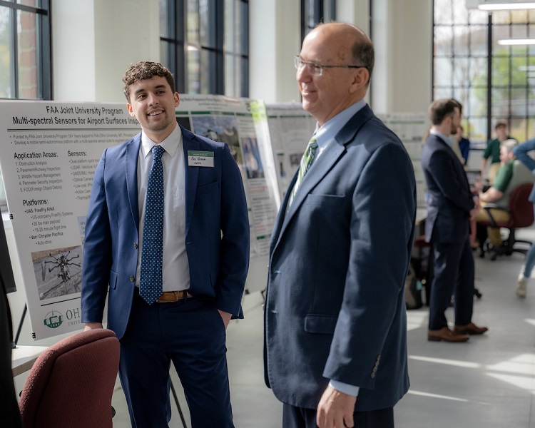 An OHIO students discusses his research presentation with a guest at the grand opening event