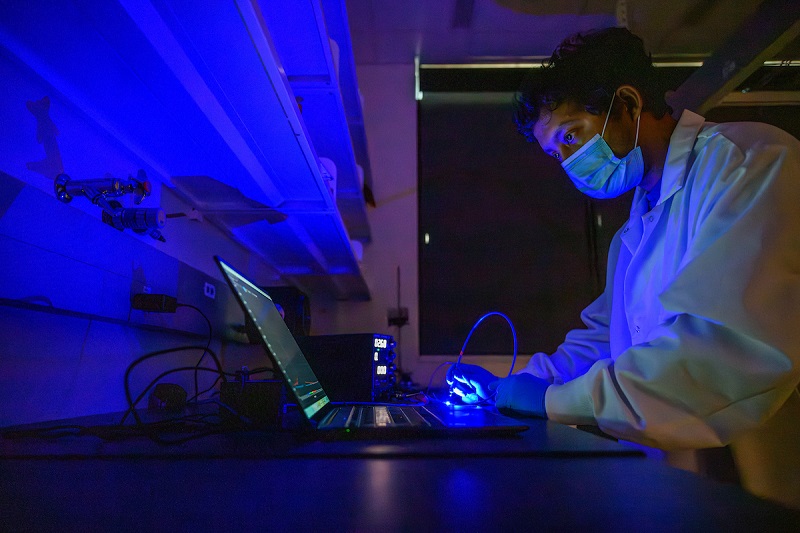 An OHIO researcher works in a lab filled with blue light in the Russ Research Opportunity Center