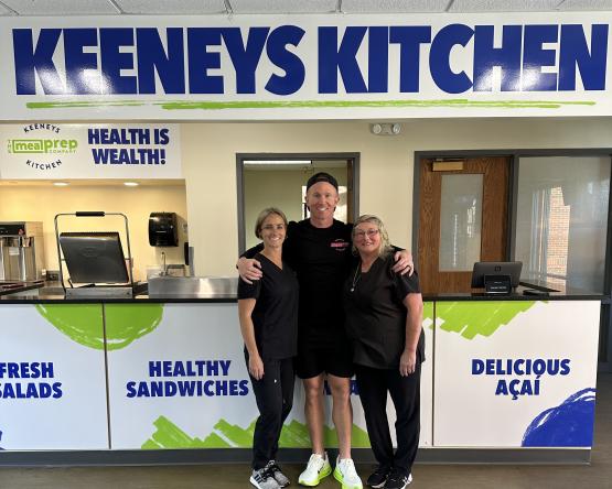  Three people dressed in black below sign reading Keeneys Kitchen 