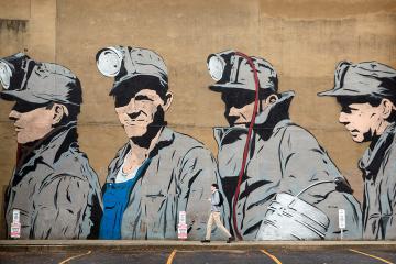 A mural depicting four coal miners on the side of a building in uptown Athens Ohio