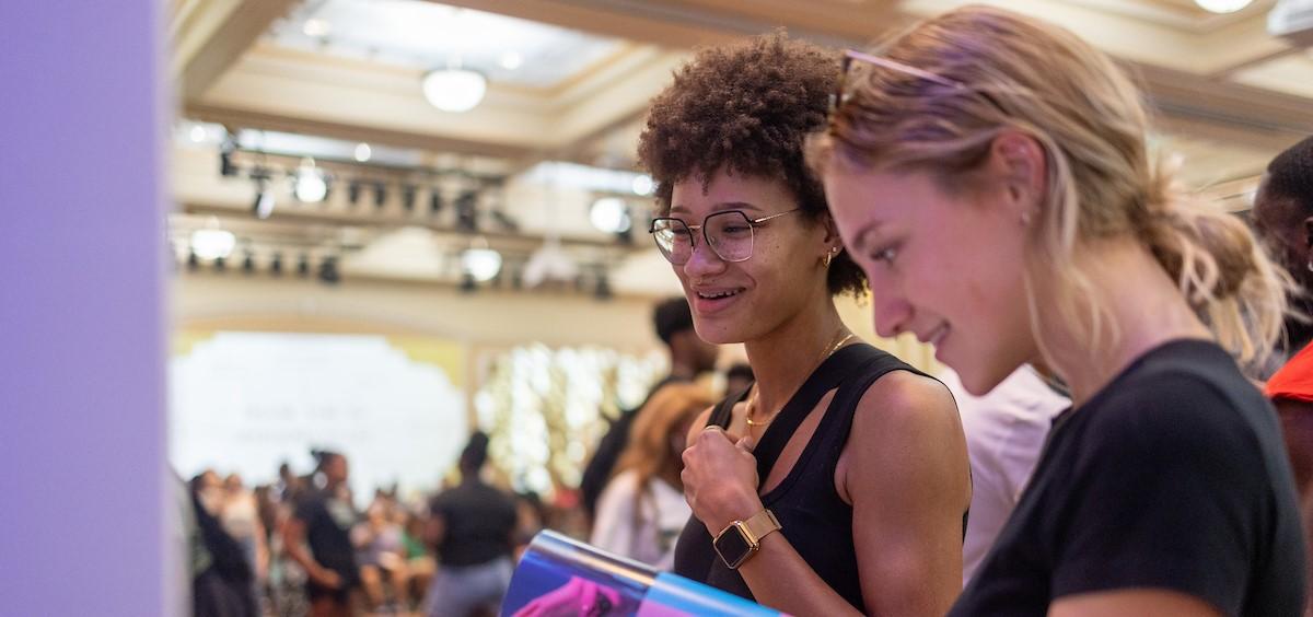 Two students looking at Ohio University materials at an event.